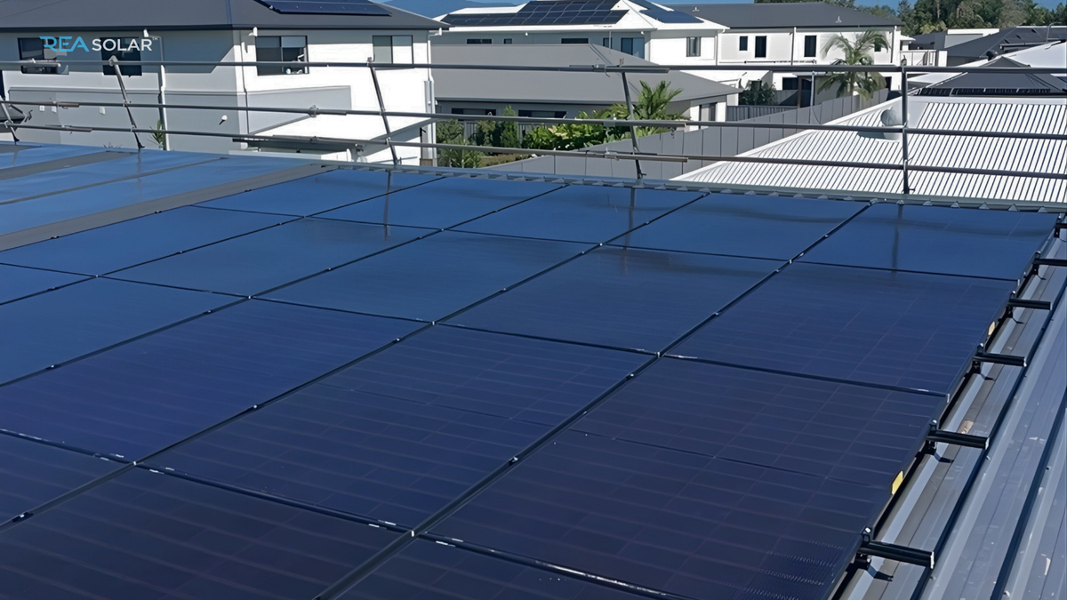 Rooftop solar panels under a sunny sky, reflecting light. Surrounded by modern buildings with more solar panels, conveying a sustainable energy theme.